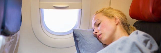 Lady traveling napping on a plane.