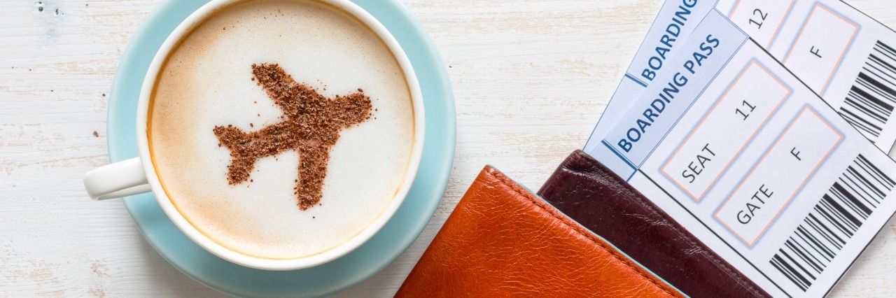 Airplane made of cinnamon in cappuccino, passports and boarding passes on white background