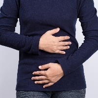woman in dark blue shirt holding her stomach