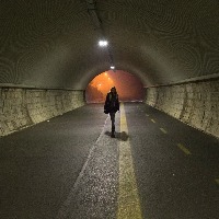 young lady walks alone trough a tunnel in the night