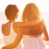 two female friends hugging and looking at sunset