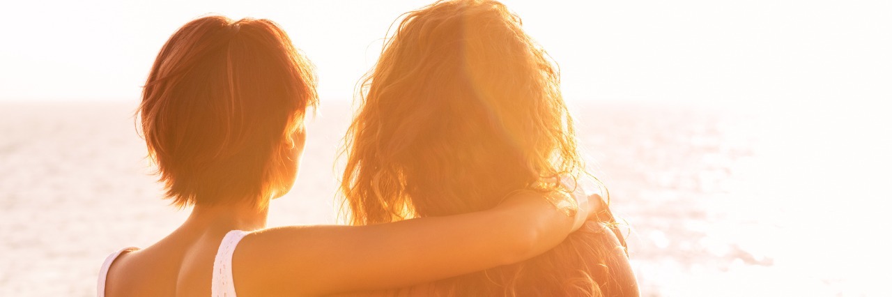 What Friends Should Know About Intracranial Hypertension two female friends hugging and looking at sunset