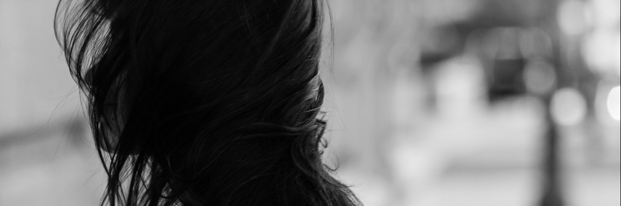 black and white photo of girl with hair blowing over her face