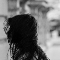 black and white photo of girl with hair blowing over her face