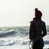 A girl looks over stormy waters in winter time