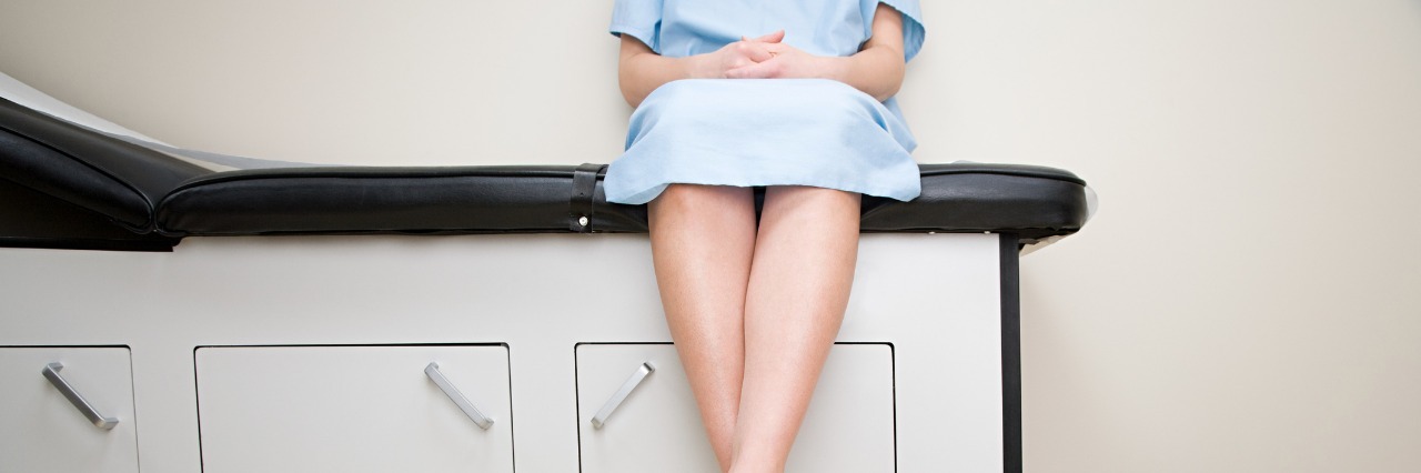 woman sitting in a doctor's office wearing a hospital gown