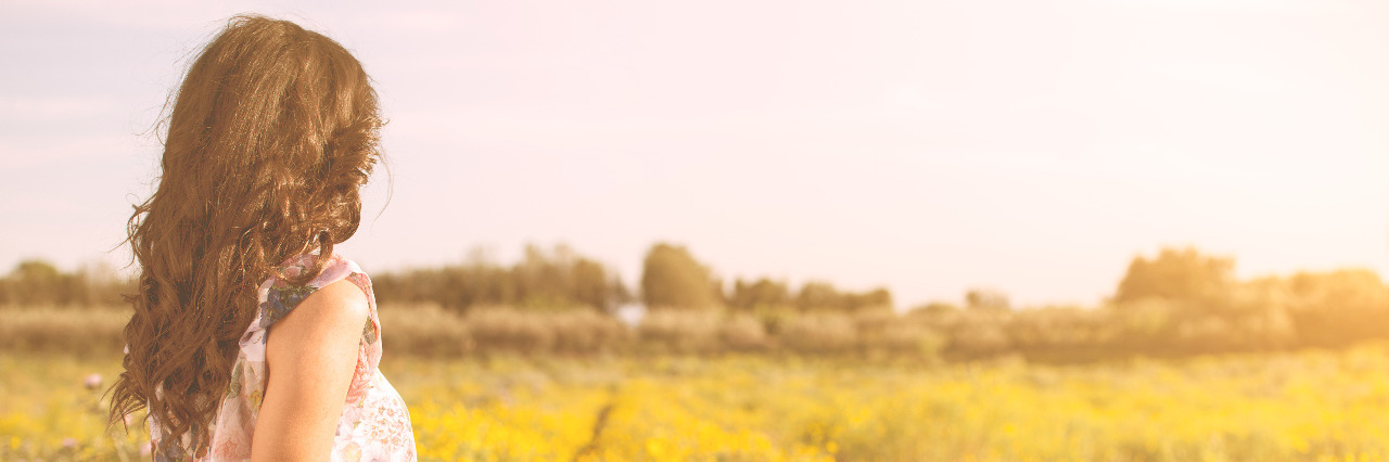 Learning Self-Acceptance With a Disability or Chronic Illness Woman sitting in a field looking at the horizon.