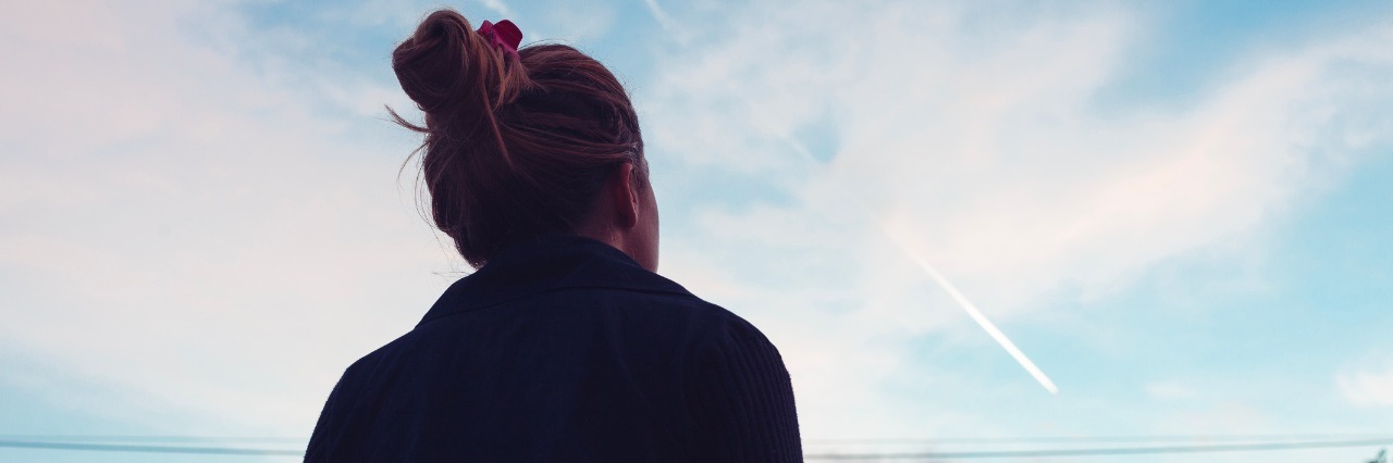 A Letter to Spoonies in America Before Trump's Inauguration The silhouette of a young woman looking at sunset in the distance.
