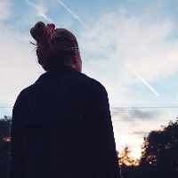 silhouette of woman looking at sunset over trees
