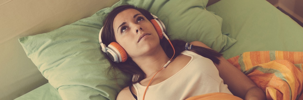 woman laying in bed listening to music