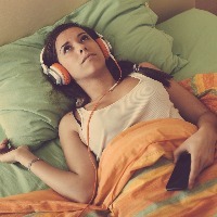 woman laying in bed listening to music