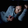 Portrait of young woman looking at the mobile phone screen at night