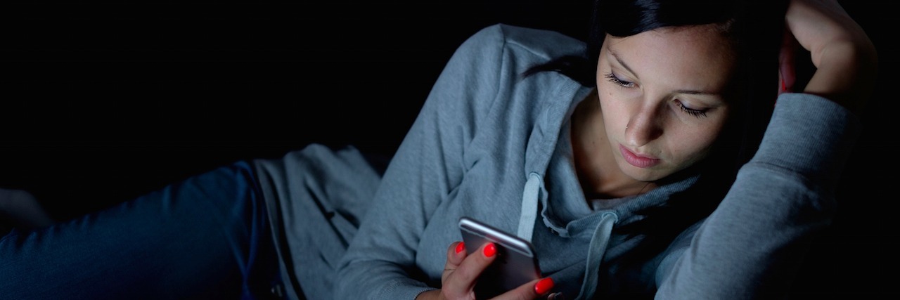 Portrait of young woman looking at the mobile phone screen at night