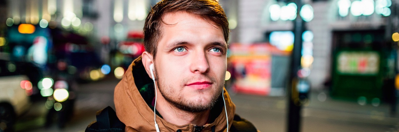 Bipolar Isn't Separate From Me, It's Who I Am A man with headphones in wearing a backpack and walking around a city