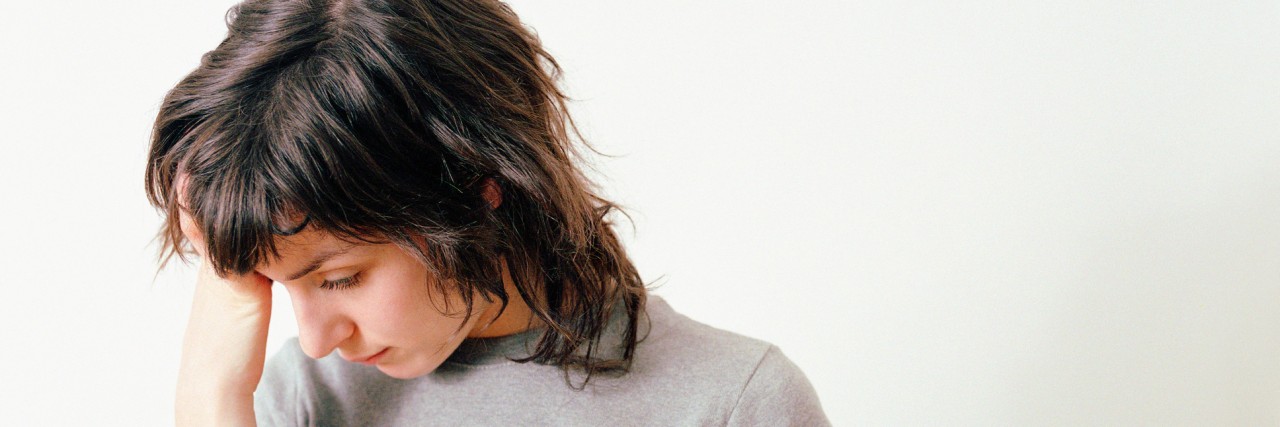 Thinking Life Is Unfair With a Mental Illness Woman looking down with hand on forehead