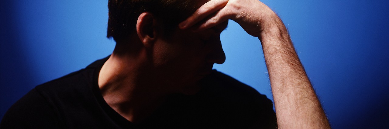 Depression: What It's Like on the Days Dominated By Suicidal Ideation side profile of a young man holding his forehead