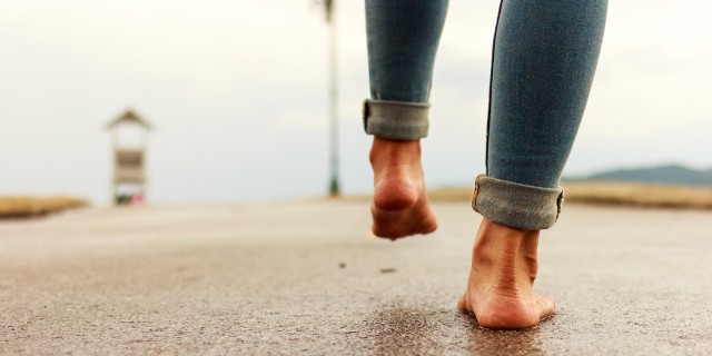 Woman walking barefoot down a path.
