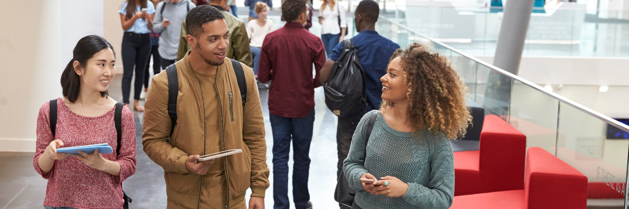 Letter to College Students Who Ask If I'm OK Students holding tablets and phone talk in university lobby.
