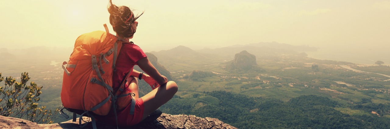 What Courage Looks Like With Hashimoto's Thyroiditis, Depression young female hiker sitting on a cliff overlooking the scenery