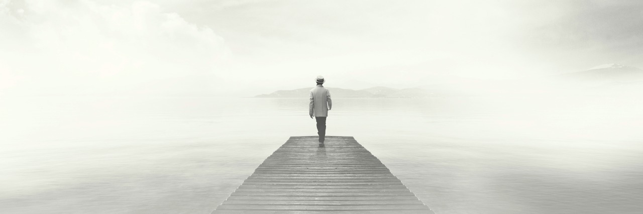 What 'Depression Brain Fog' Feels Like Man walking on a boardwalk in the fog