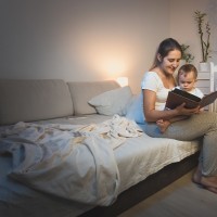 Mother holding baby boy on knees and reading book