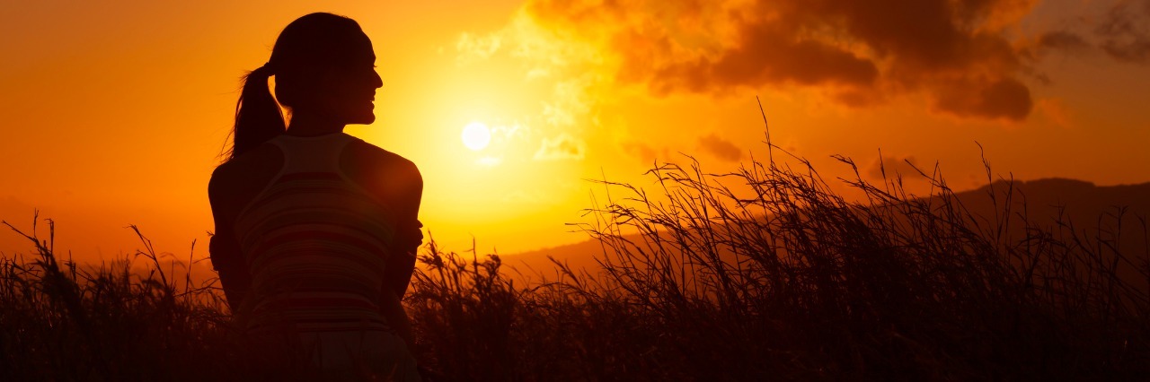 Woman watches the beautiful sunset/sunrise.