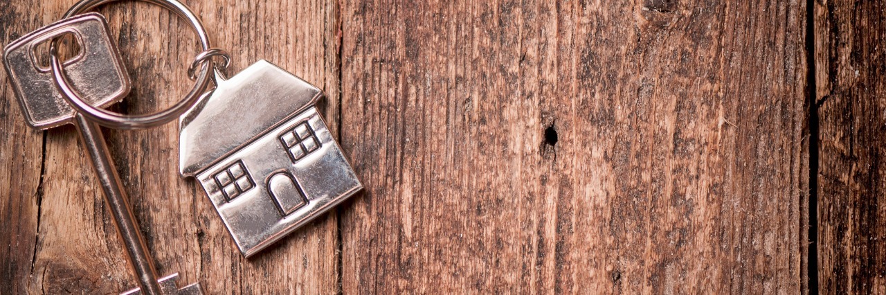 Moving in With Your Boyfriend or Girlfriend With Mental Illness House key on a house shaped keychain on wooden table