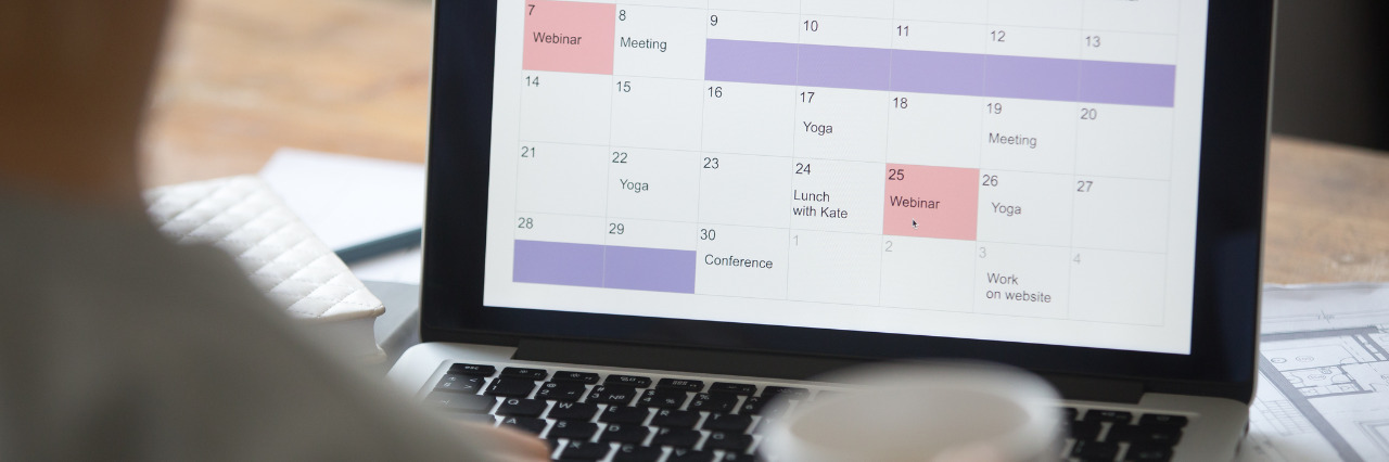 Open laptop on the desk, planner calendar on the screen.