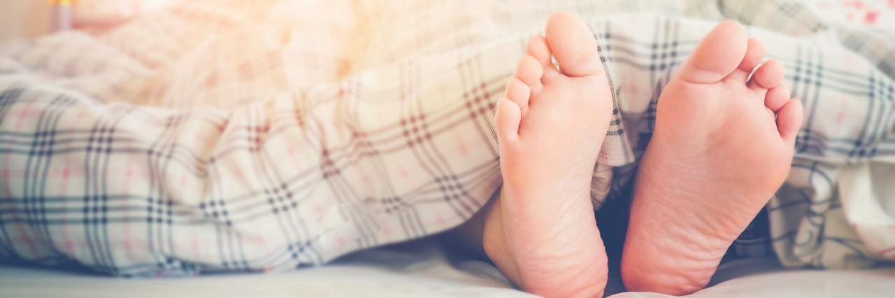 How I Pace Myself to Deal With Chronic Pain From Fibromyalgia Close up feet of women sleeping on bed in Morning