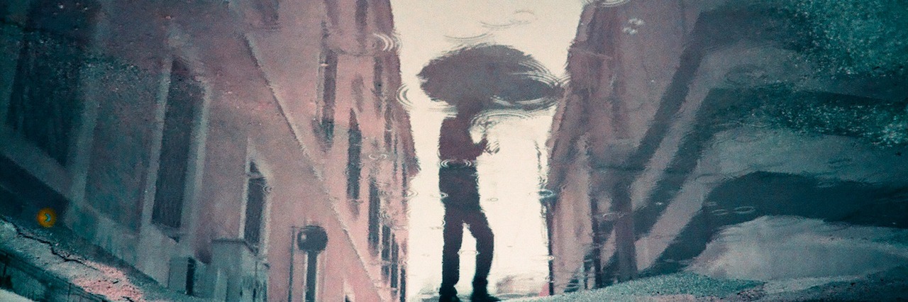 A reflection of a man holding an umbrella