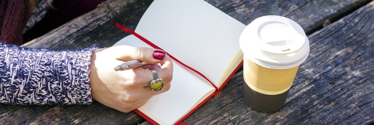 A Letter to Anorexia From Someone in Recovery woman writing in her journal sitting outside on a picnic table