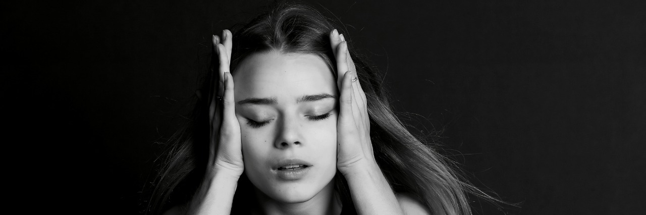 Breakdown of an Autistic Meltdown young girl holding her head in her hands against black background