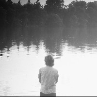 Woman standing in front of tree-lined lake