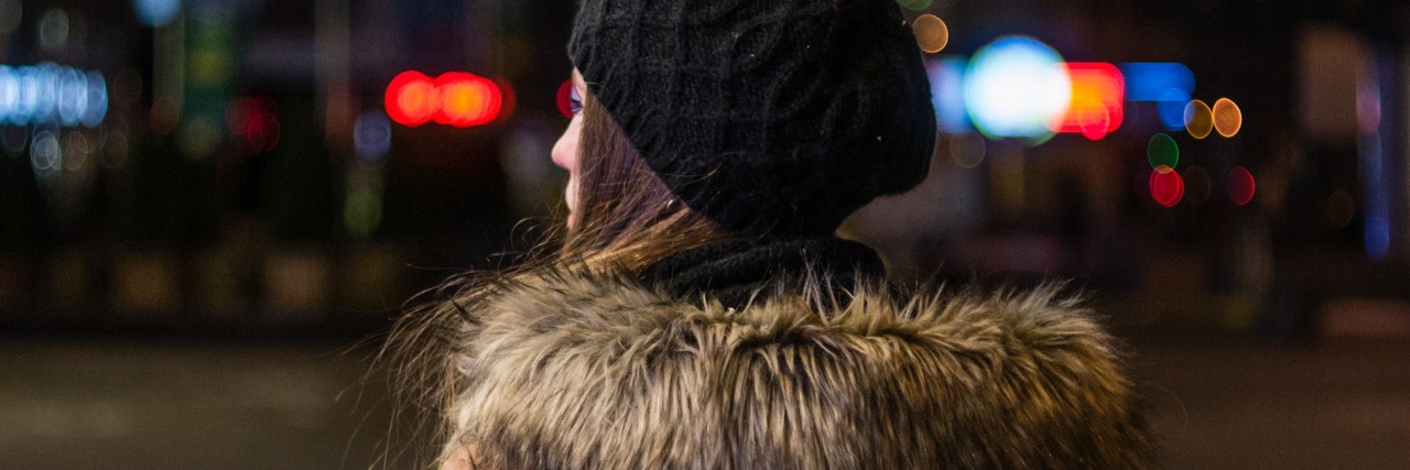 Lonely young woman walking through night city street