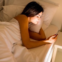 A woman in her bed looking at her phone