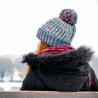 woman sitting on bench in snowy weather