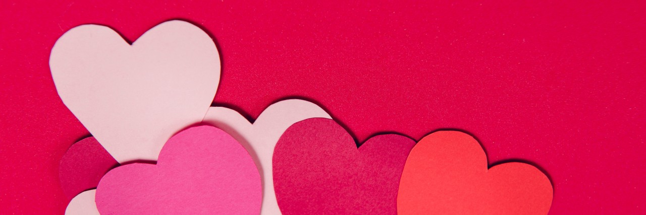 Colorful paper hearts on red paper background