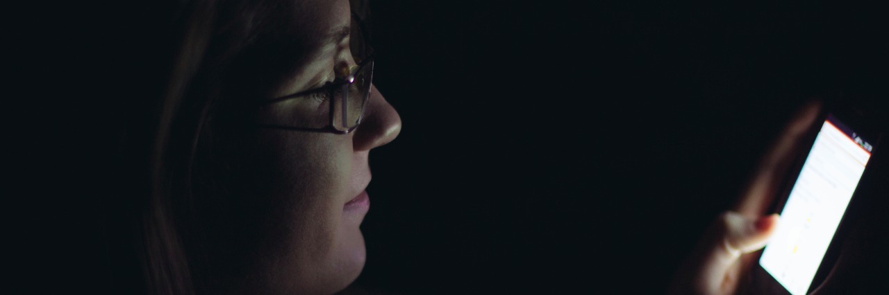 Missing Tests and Exams due to Anxiety Young woman using mobile phone in dark room at night