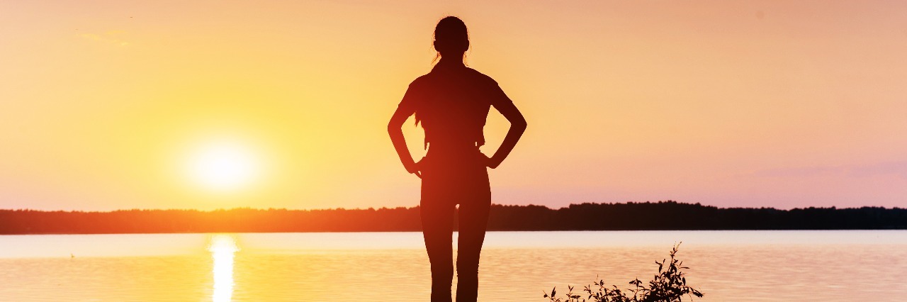 Supporting Yourself and Being Strong With Ehlers-Danlos Syndrome silhouette of woman standing next to lake at sunset