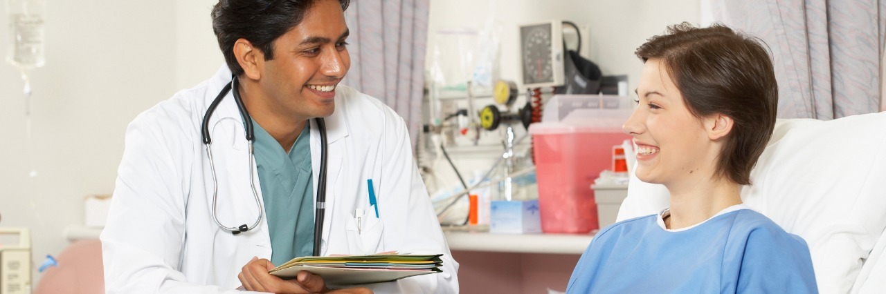 Tips for Going to Doctor Appointments female patient laying in hospital bed and smiling and talking with male doctor