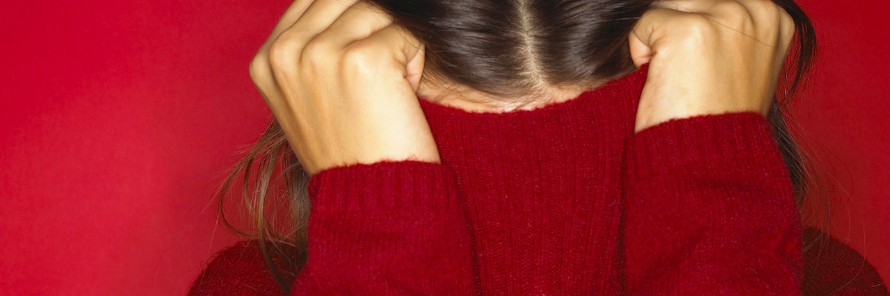 Woman hiding in red turtleneck