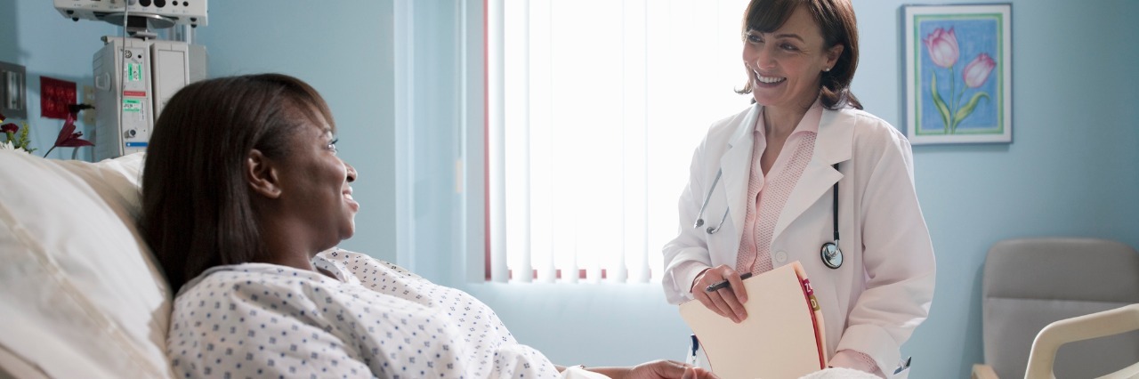Patient Rights and Handling Mistreatment From Doctors female patient laying in a hospital bed and talking to her doctor