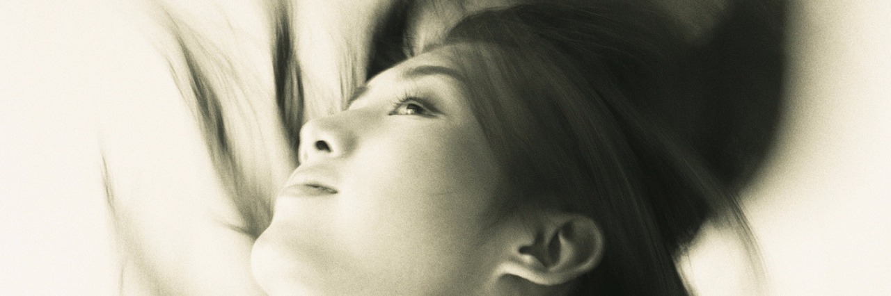 Borderline Personality Disorder and Being Stuck in a 'Black High' Image of a Young Adult Woman Flipping her Hair Back, Smiling, Blurred Motion, Side View