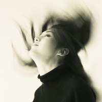 Image of a Young Adult Woman Flipping her Hair Back, Smiling, Blurred Motion, Side View