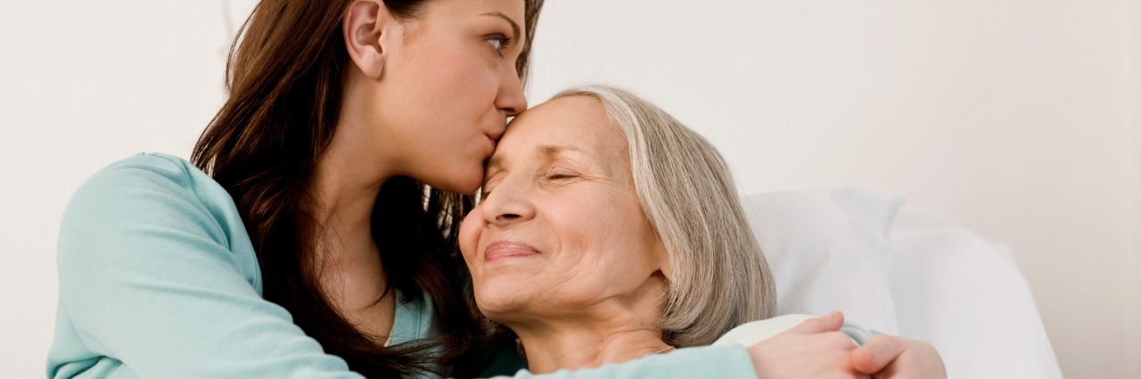 How to Be a Good Patient Advocate woman kissing elderly patient laying in a hospital bed