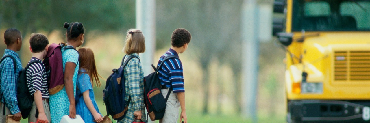 How to Support Children With Autism During Back-to-School Transitions side profile of students standing in line for a school bus