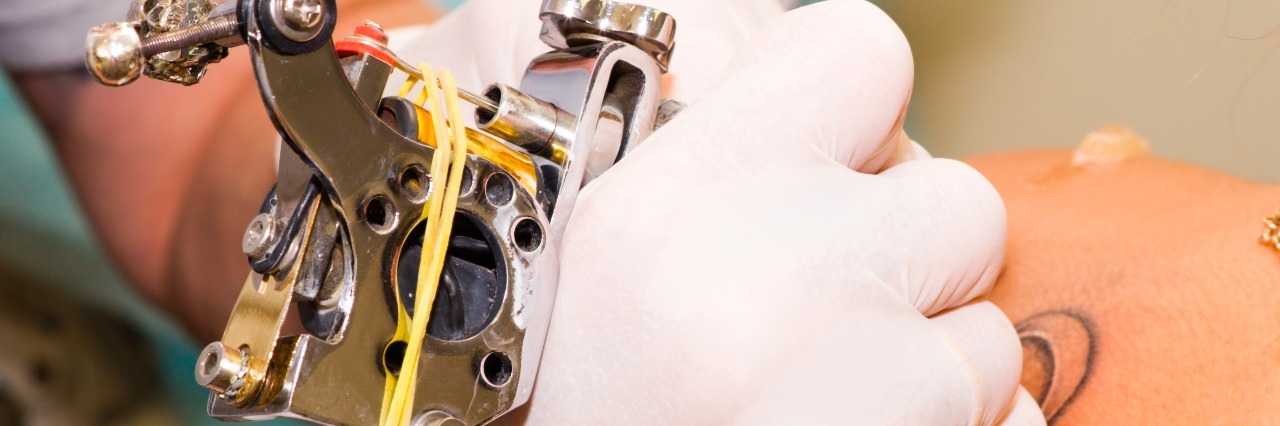 Why I Tattooed a Symbol of Lupus on Myself Forever tattoo artist using tattoo gun on woman