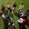 group of people sitting on chairs in a circle outside