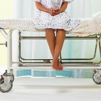 Female patient sitting on gurney in hospital gown