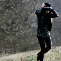 Woman wearing hat, walking near a tree in a field